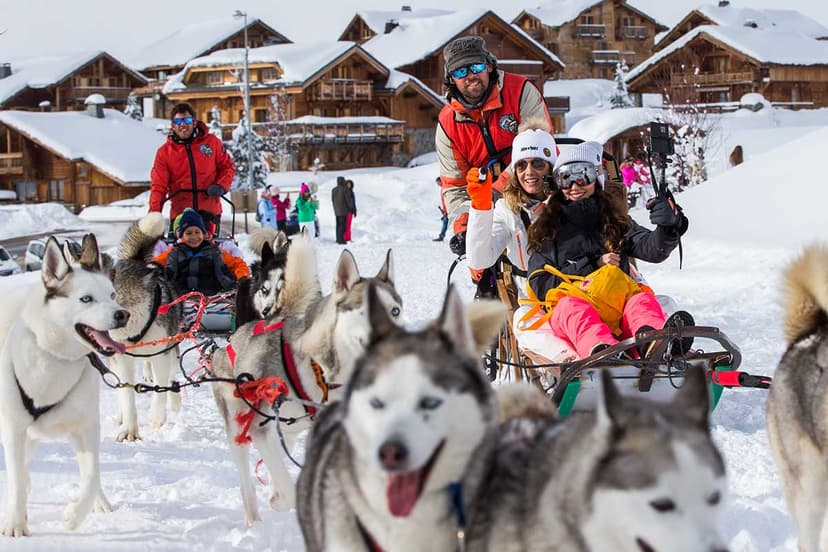 Family enjoying dog sledding ride by huskies in French Alps